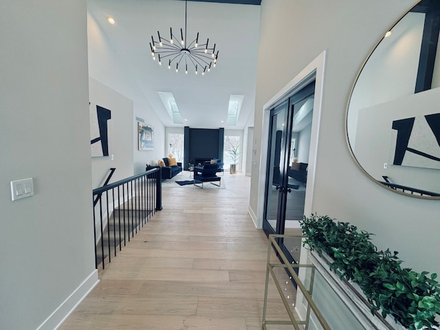 hall with a skylight, an inviting chandelier, and light hardwood / wood-style floors