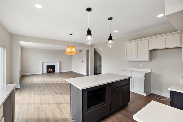 kitchen with light countertops, hanging light fixtures, wood finished floors, and white cabinetry