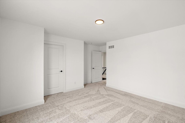 empty room with baseboards, visible vents, and light colored carpet