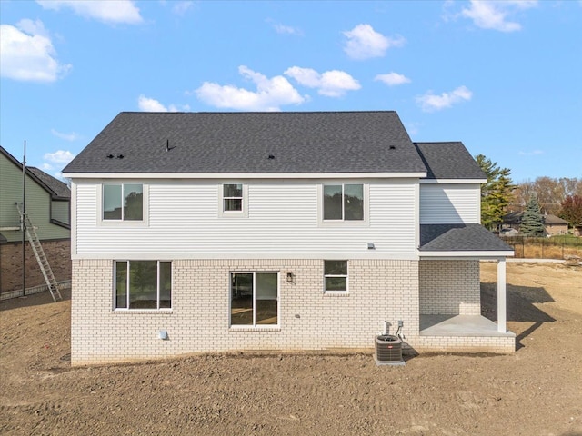 rear view of property with a patio area, brick siding, roof with shingles, and central AC unit