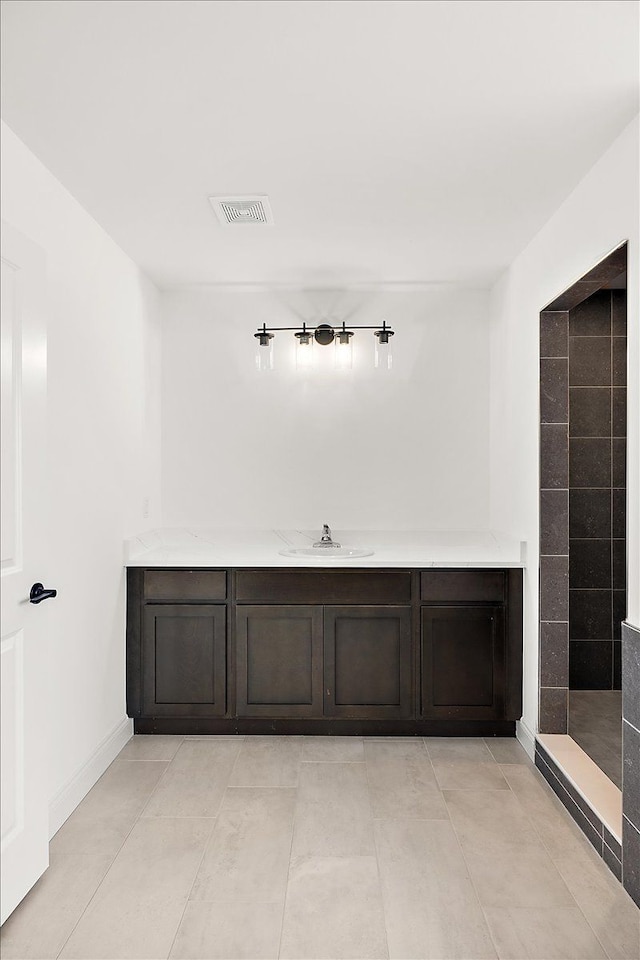 full bath featuring tile patterned flooring, a sink, visible vents, baseboards, and tiled shower