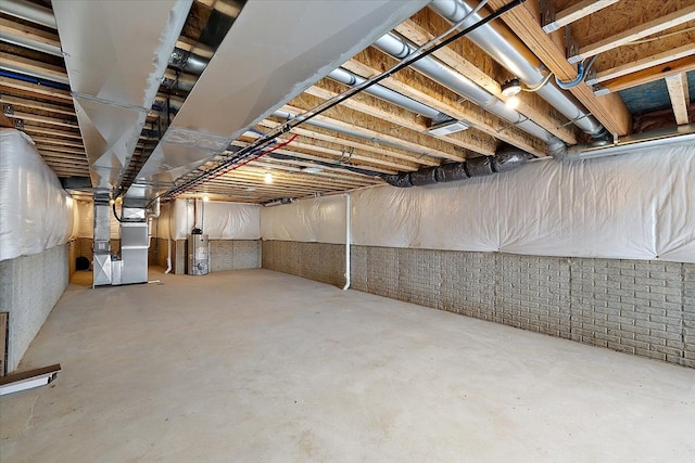 unfinished below grade area with gas water heater, brick wall, and heating unit