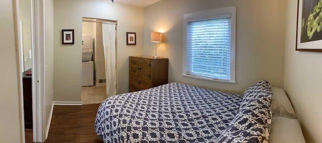 bedroom with stacked washer and clothes dryer and dark hardwood / wood-style floors