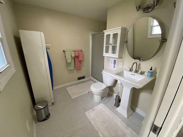 bathroom featuring a shower with door, toilet, and tile patterned floors