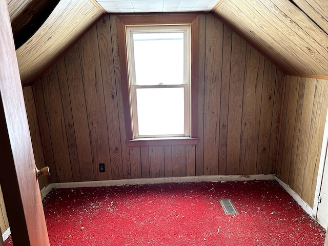 bonus room with vaulted ceiling, carpet, and wooden walls