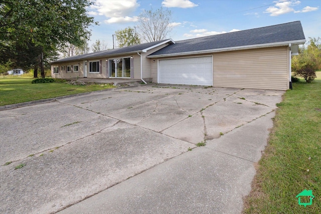 ranch-style home with concrete driveway, a front lawn, and an attached garage