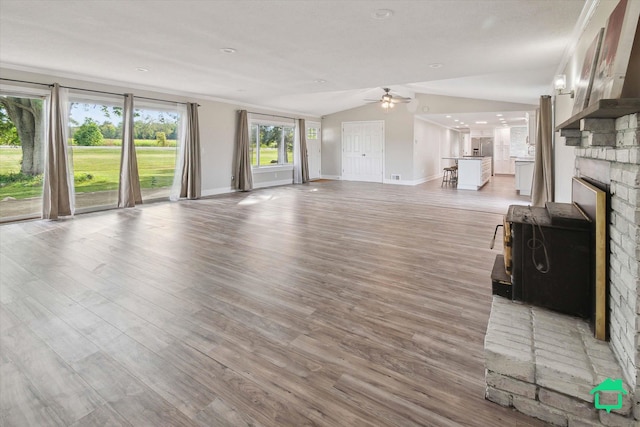 unfurnished living room featuring lofted ceiling, ceiling fan, baseboards, and light wood-style floors