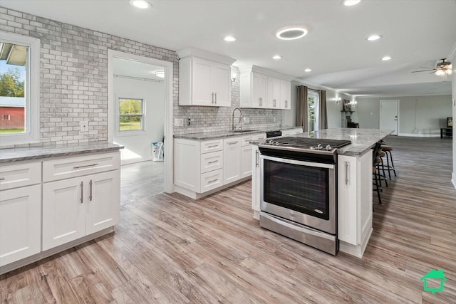 kitchen featuring light stone countertops, white cabinets, and gas range