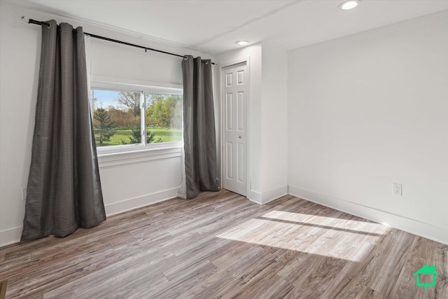 empty room featuring light wood-type flooring, baseboards, and recessed lighting