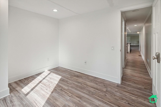 unfurnished room featuring recessed lighting, wood finished floors, and baseboards