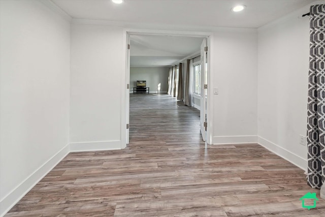 corridor featuring ornamental molding, light wood-type flooring, and baseboards