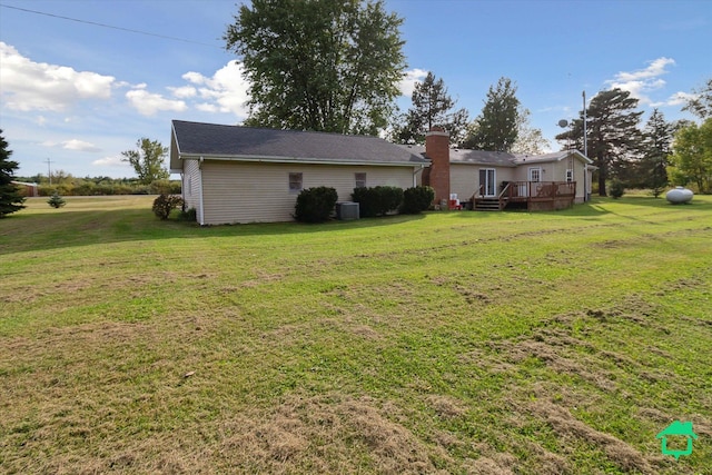 exterior space with cooling unit, a chimney, a yard, and a deck