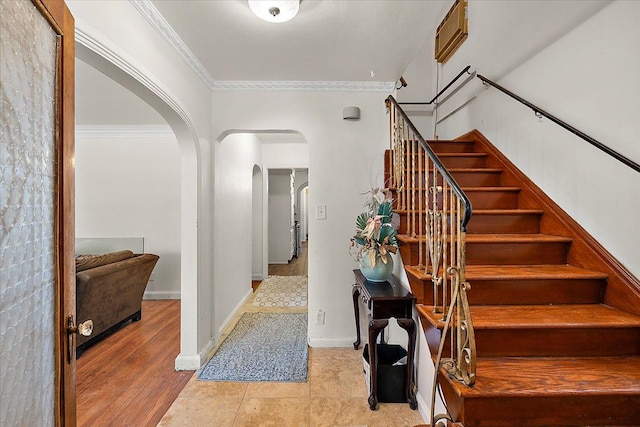 foyer entrance featuring ornamental molding, baseboards, stairs, and arched walkways