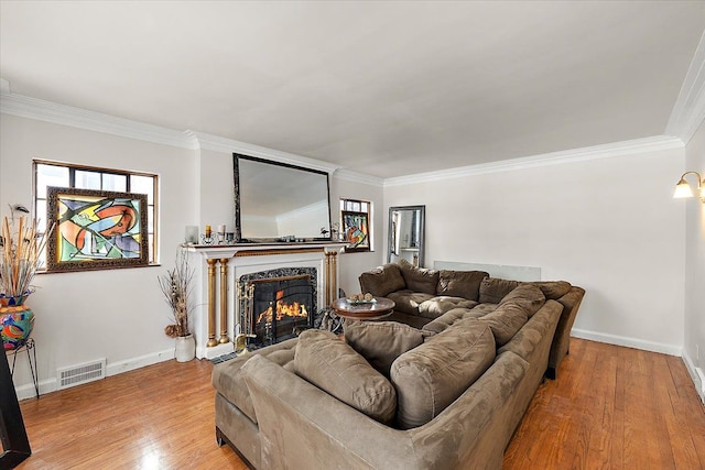 living area featuring crown molding, visible vents, baseboards, light wood-style floors, and a premium fireplace