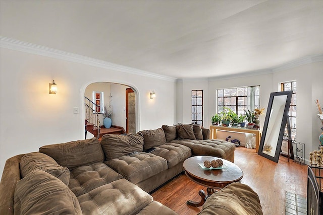 living area with ornamental molding, stairway, light wood-type flooring, and arched walkways