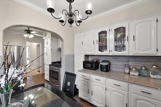 kitchen with arched walkways, stainless steel gas range oven, white cabinets, and black microwave