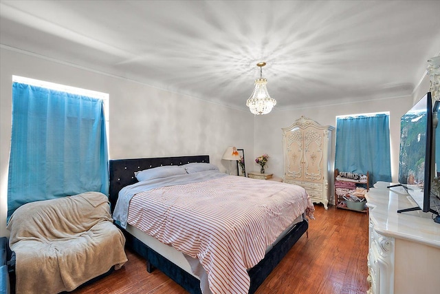 bedroom featuring dark wood finished floors and a chandelier