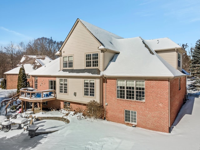 snow covered back of property with a deck