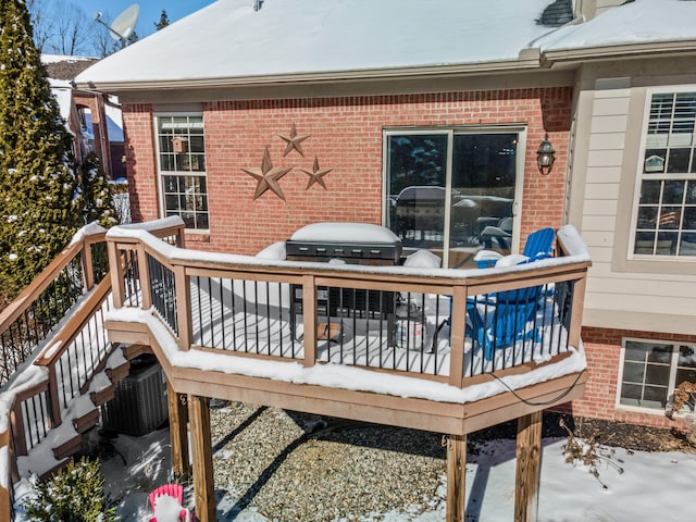 snow covered deck with central AC unit and area for grilling