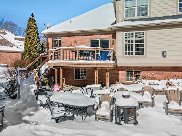 snow covered back of property with a wooden deck