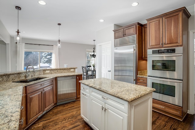 kitchen featuring appliances with stainless steel finishes, decorative light fixtures, sink, and light stone countertops