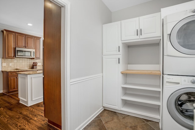 washroom with cabinets and stacked washer and clothes dryer