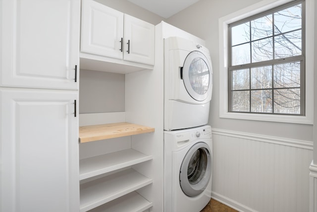 washroom featuring stacked washer / drying machine and cabinets