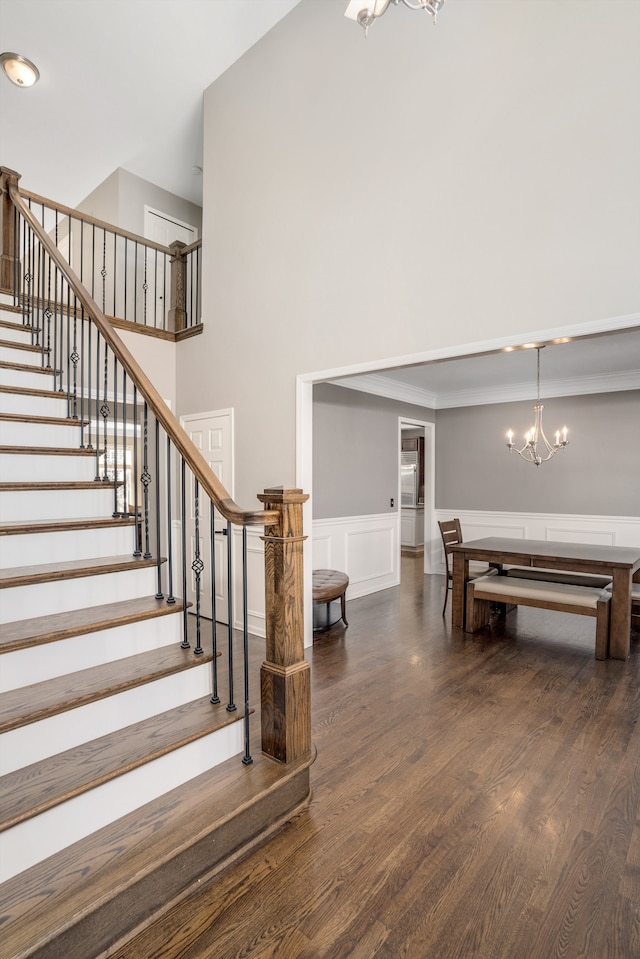 stairs with a chandelier, a high ceiling, and hardwood / wood-style floors