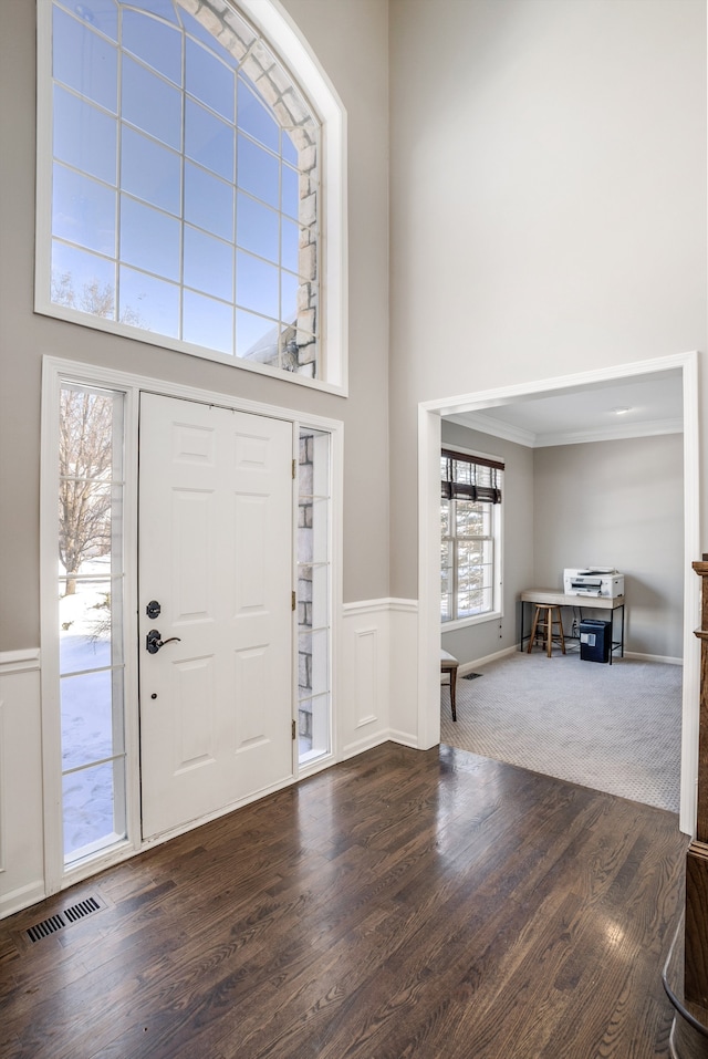 entrance foyer with dark hardwood / wood-style floors, crown molding, and a high ceiling