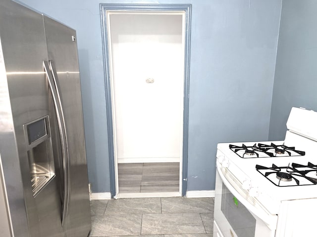 kitchen with white range with gas stovetop, white cabinets, and stainless steel fridge with ice dispenser