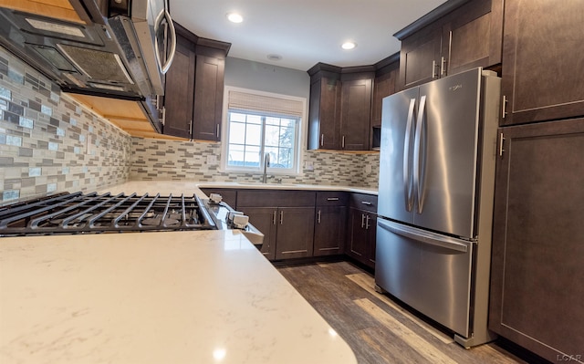 kitchen featuring sink, dark wood-type flooring, stainless steel fridge, dark brown cabinetry, and decorative backsplash