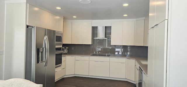 kitchen featuring appliances with stainless steel finishes, wall chimney range hood, backsplash, dark hardwood / wood-style flooring, and white cabinetry