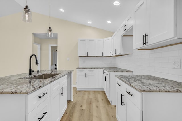 10781 Woodbrook Dr, Cement City, MI 49233 - kitchen with lofted ceiling, light stone countertops, light wood finished floors, tasteful backsplash, and pendant lighting