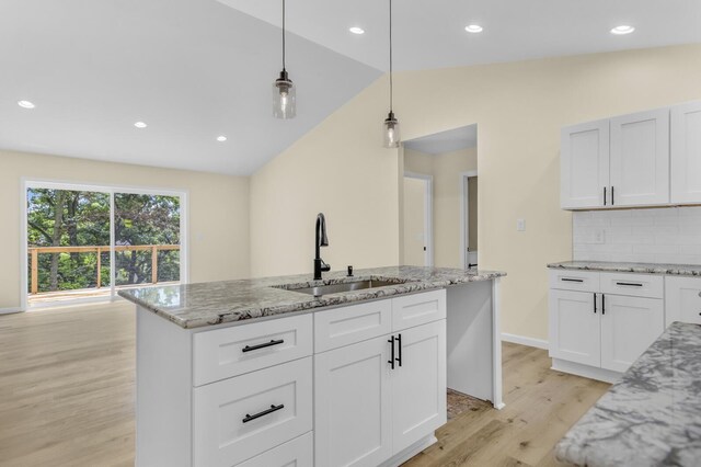 10781 Woodbrook Dr, Cement City, MI 49233 - kitchen featuring light wood-type flooring, lofted ceiling, backsplash, decorative light fixtures, and light stone countertops