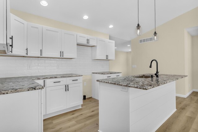 10781 Woodbrook Dr, Cement City, MI 49233 - kitchen with light stone countertops, light wood-style floors, backsplash, white cabinetry, and recessed lighting