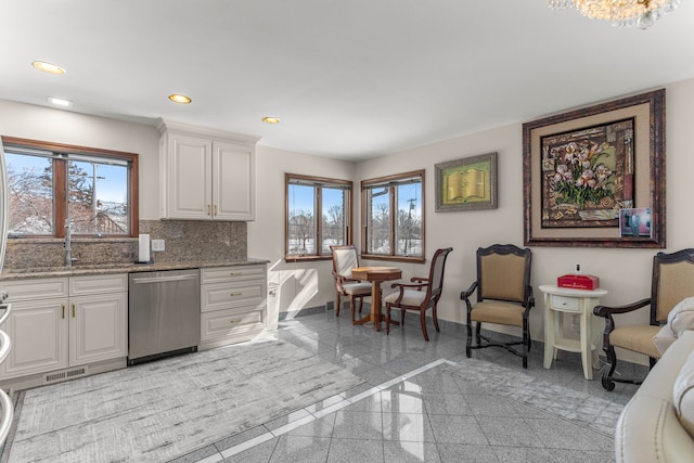 kitchen featuring stainless steel dishwasher, white cabinets, light stone counters, and a healthy amount of sunlight