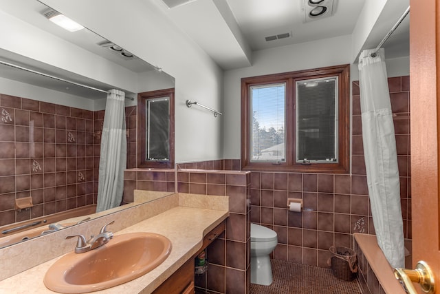 bathroom featuring toilet, walk in shower, tile walls, tile patterned floors, and vanity