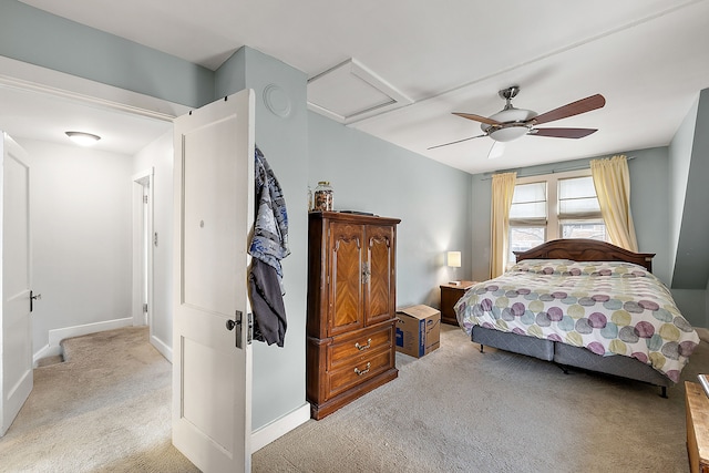 bedroom with a ceiling fan, attic access, light colored carpet, and baseboards