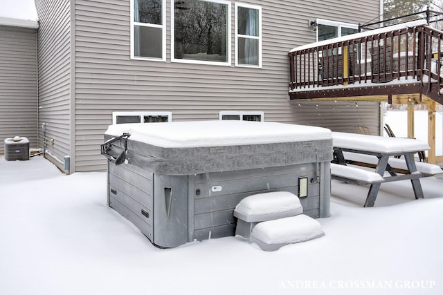 snow covered patio featuring a hot tub and a balcony