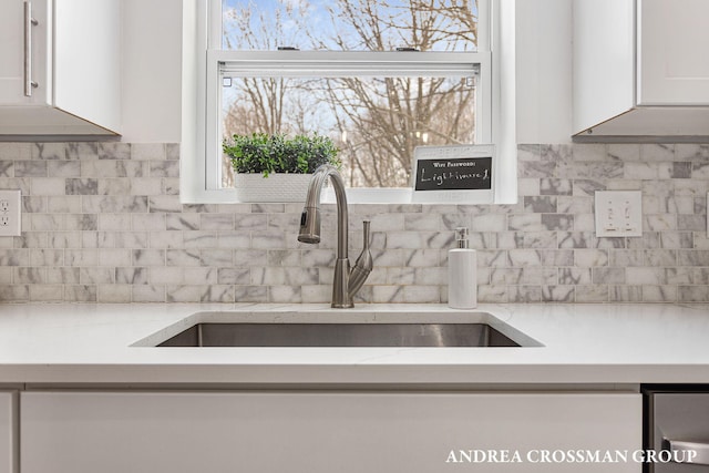 kitchen with sink, white cabinetry, light stone countertops, and backsplash