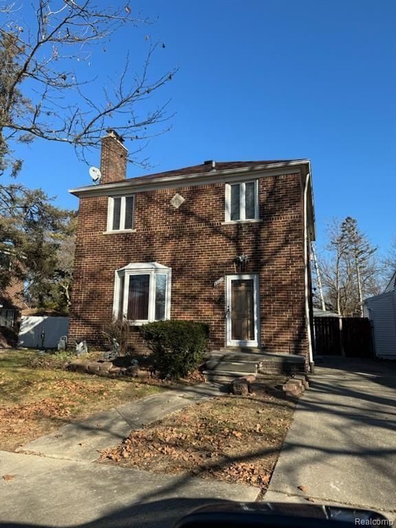 rear view of property with brick siding and a chimney