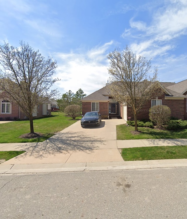 view of front of house featuring driveway, a garage, a front lawn, and brick siding