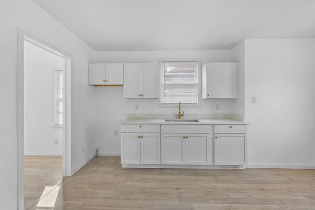 kitchen with sink, white cabinets, and light hardwood / wood-style floors