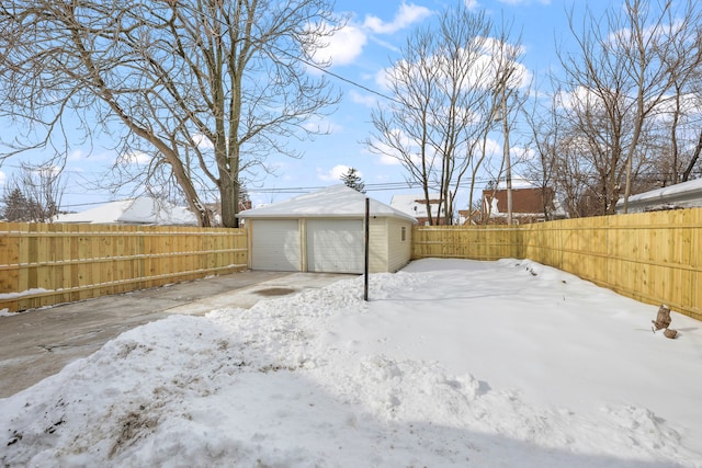 yard covered in snow featuring a garage and an outbuilding