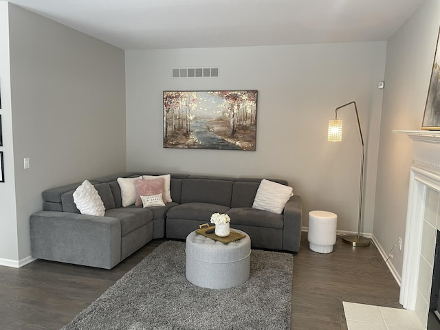 living room with dark hardwood / wood-style floors and a tiled fireplace