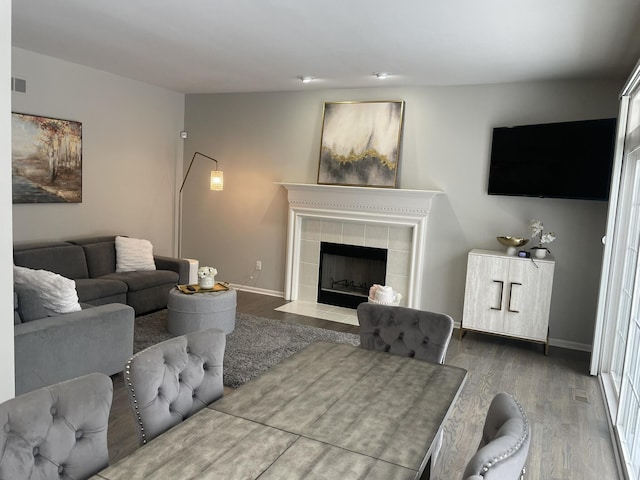 living room featuring a tiled fireplace and dark wood-type flooring