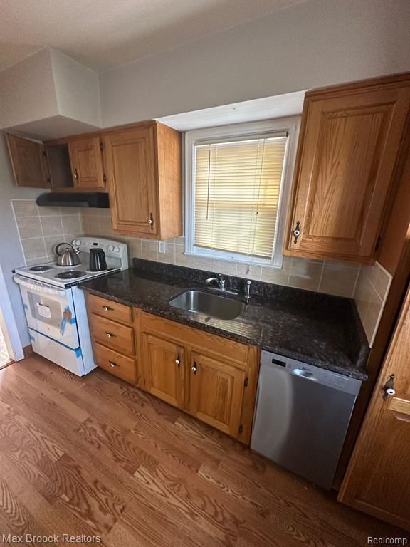 kitchen featuring white electric range oven, light hardwood / wood-style floors, sink, tasteful backsplash, and dishwasher