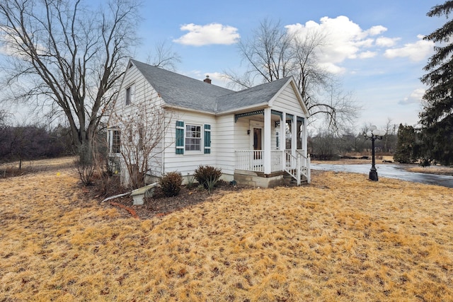 view of front of property featuring covered porch, a shingled roof, and a chimney