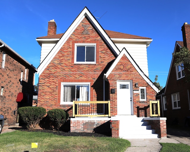 tudor house featuring a front yard and brick siding