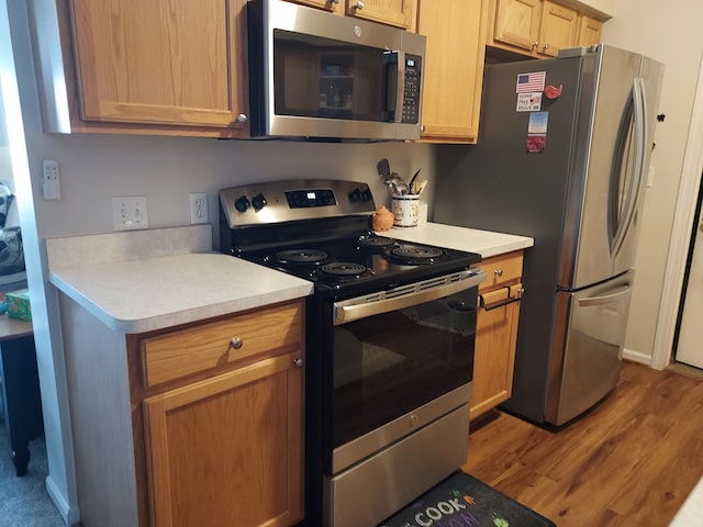 kitchen featuring appliances with stainless steel finishes, light countertops, and wood finished floors